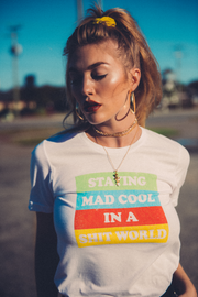Girl with pony tail hairstyle wearing white cotton t-shirt that says Staying Mad Cool in a shit world.